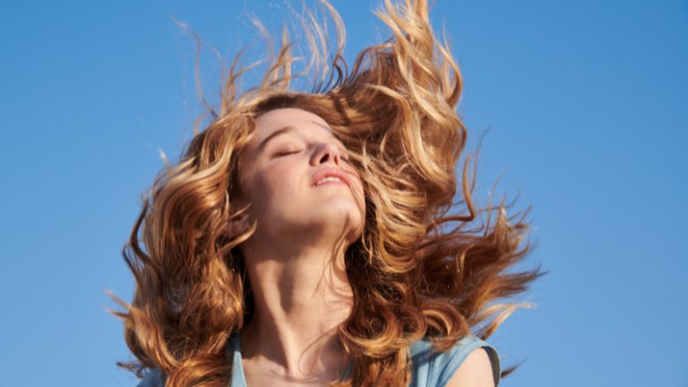 בחורה עם שיער מתנופף על רקע כחול