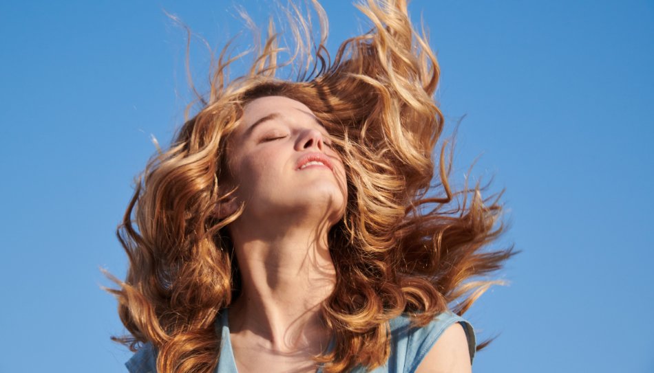 בחורה עם שיער מתנופף על רקע כחול