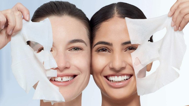 שתי נשים מחייכות ומסירות חצי ממסכת טישו